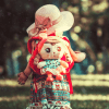 Imagem ilustrativa para falar de retrospectiva. Uma menina com uma mochila de boneca caminhando em um lugar gramado. Sobre redescobrir nossa missão.